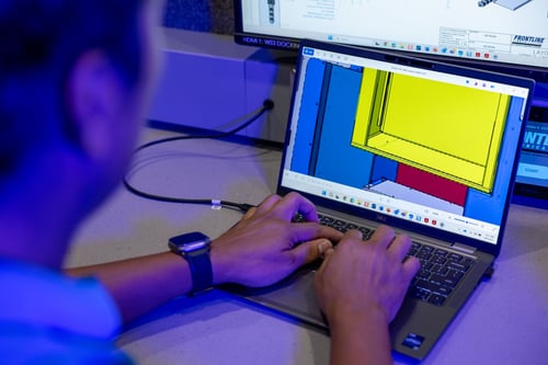 A Frontline Communications team member typing on a laptop.