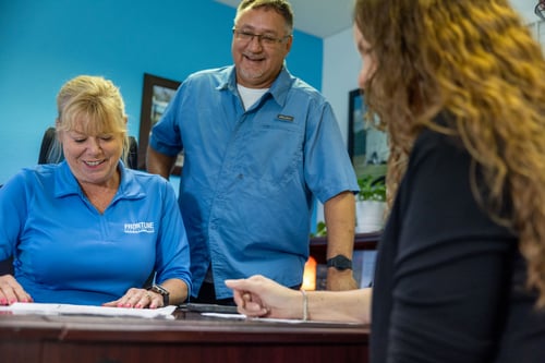 Three Frontline Communications team members gathered around a desk in an office.