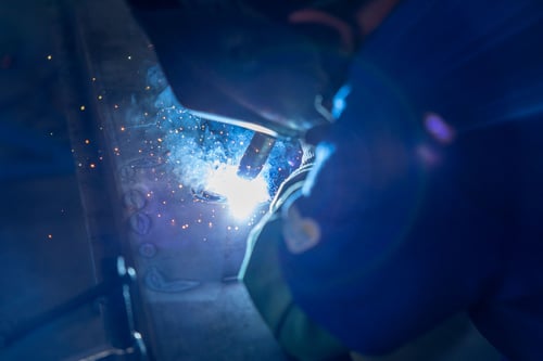 A Frontline Communications team member welding in the manufacturing facility.