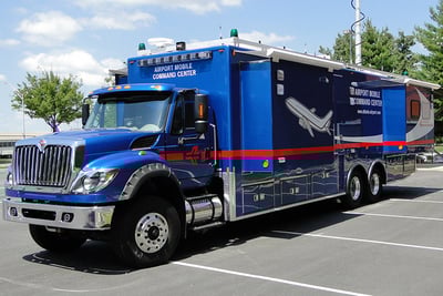 Atlanta's blue airport mobile command center is parked in a lot with a raised tower and its side compartments extended.