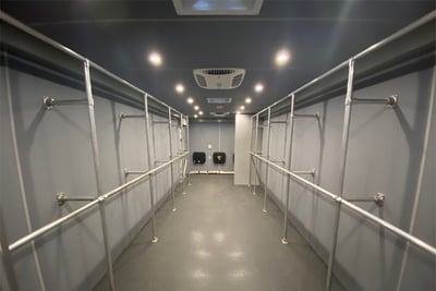 The interior of a field decontamination vehicle shows built-in storage racks and seating.