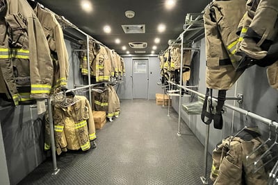 The interior of a field decontamination vehicle shows built-in storage racks and turnout gear.