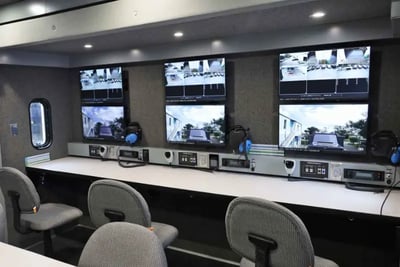 The interior of a command vehicle showing a desk with multiple screens.