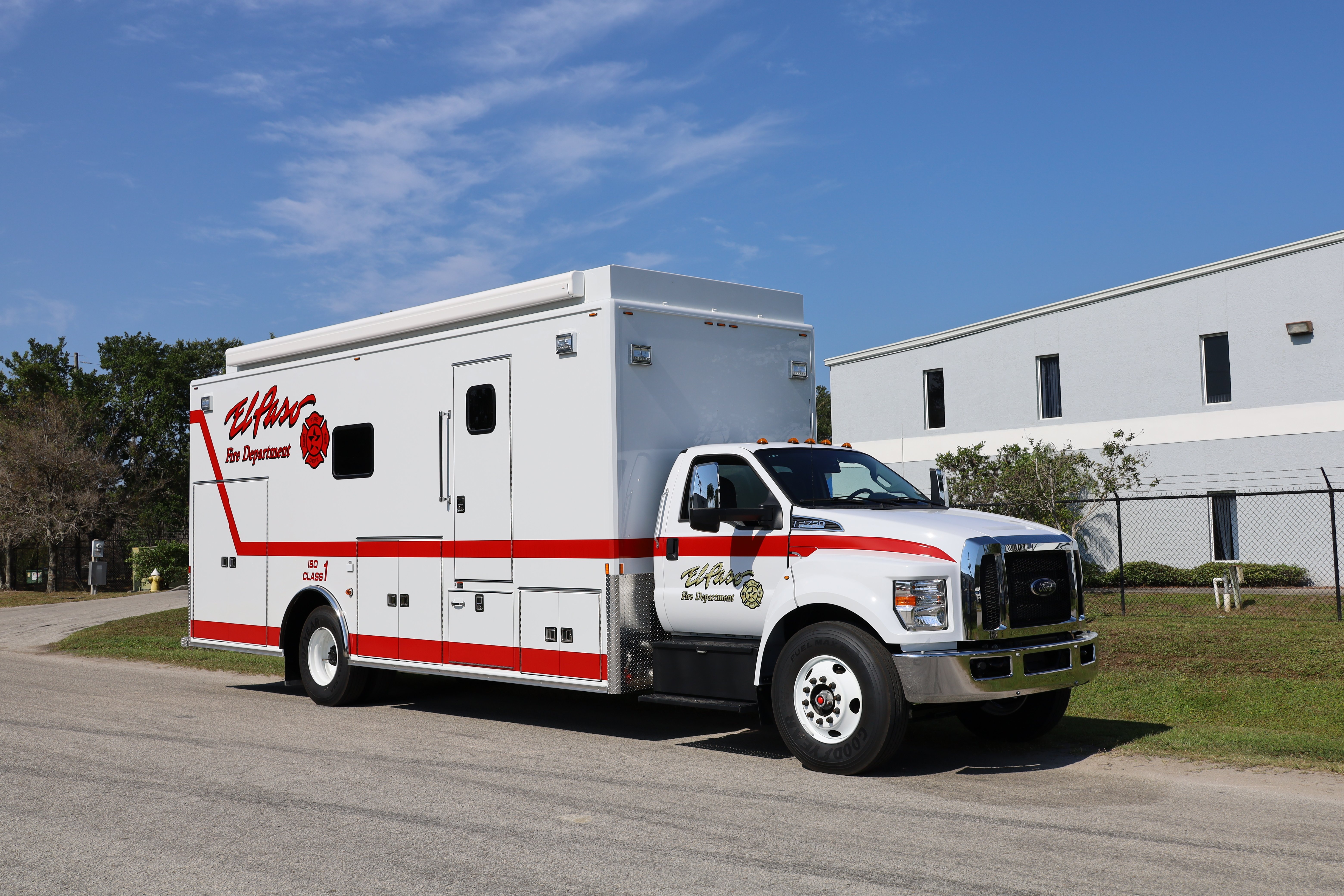 Frontline Communications Rehab unit parked outside near a building on a sunny day.