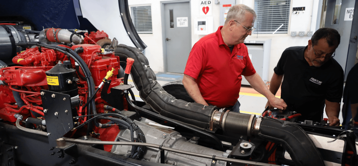 Two technicians work on an engine