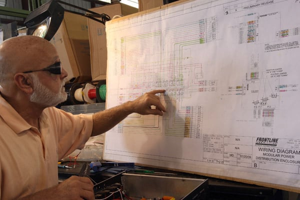 A man pointing at engineering blueprints for a Frontline Communications vehicle.