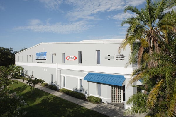 Frontline Communications building near palm trees on a sunny day.