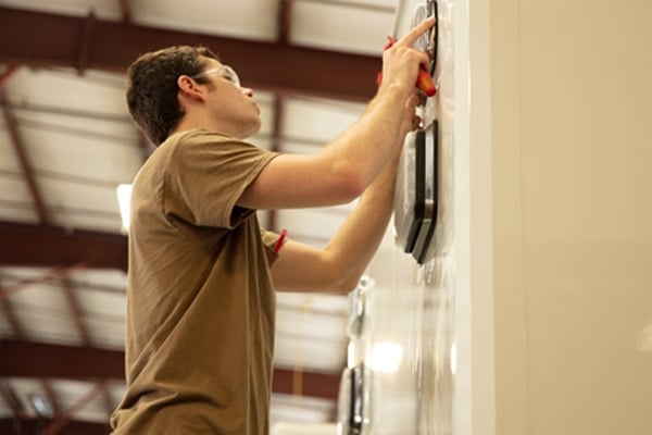 A man hanging an item on the wall inside of the Frontline Communications building.