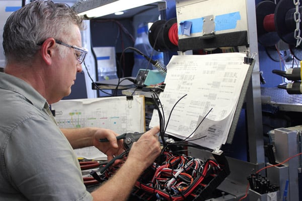 A man performing service to an electrical panel in the Frontline Communications building.