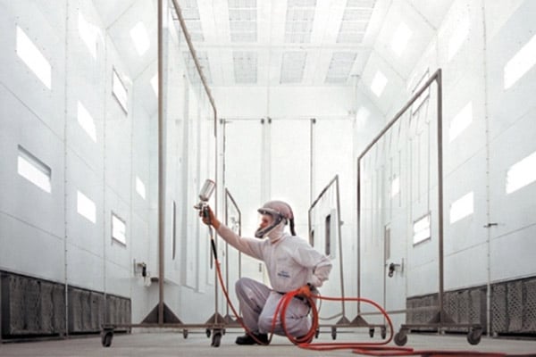 A person painting a part of a Frontline Communications vehicle in the manufacturing facility.