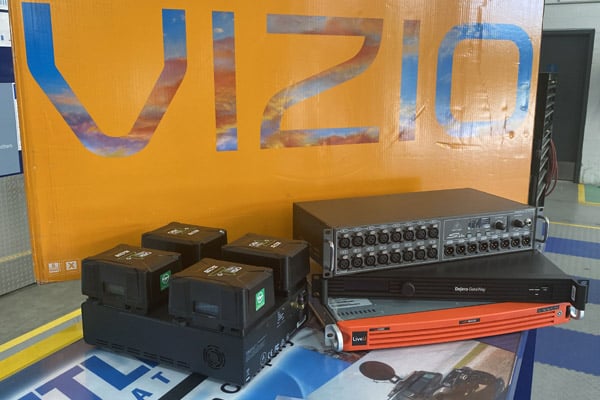 Parts of a Frontline Communications vehicle in front of a Vizio sign.