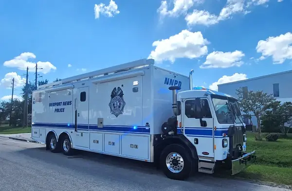 A Frontline Communications Mobile Command Vehicle for Newport News Police Department parked outside on a cloudy day.