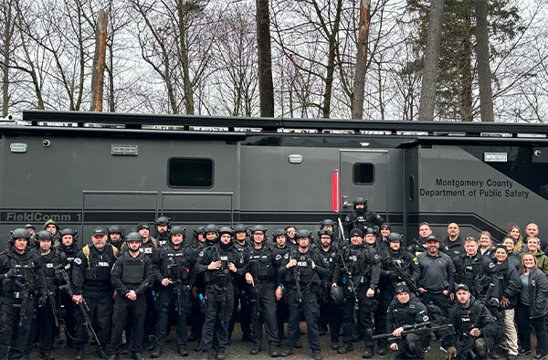 Montgomery County Department of Public Safety gathered around their Mobile Command Vehicle on a cloudy day.