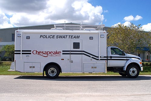 SWAT vehicle parked outside near the Frontline Communications vehicle on a cloudy day.