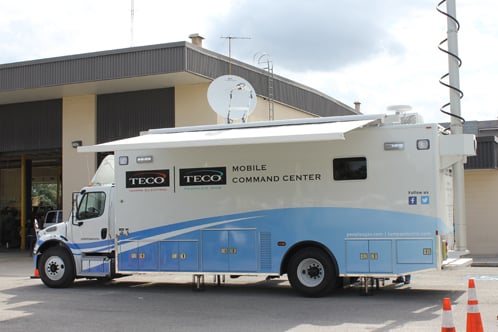 Frontline Communications Specialty Vehicle Mobile Command Center parked outside of a building on a cloudy day. 