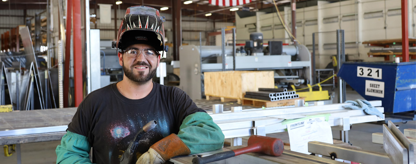 A welder standing beside a work table at the Frontline Communications building.