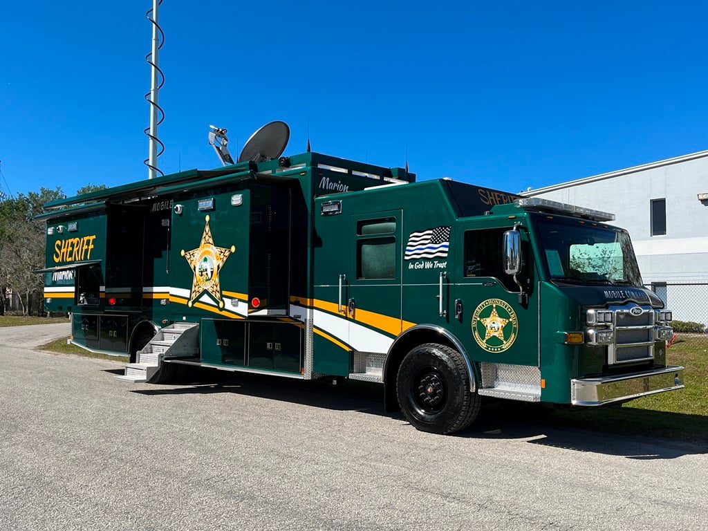Frontline Communications green Large Mobile Command vehicle parked outside the building on a sunny day. 