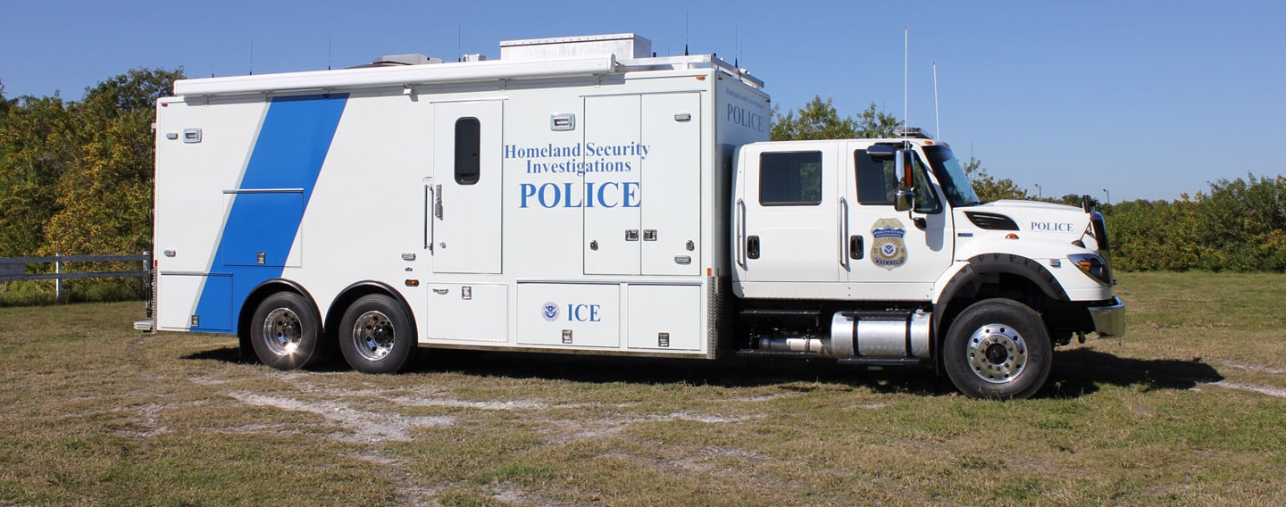 Frontline Communications Federal Mobile Command vehicle for Homeland Security Investigations parked outside on the grass on a sunny day. 