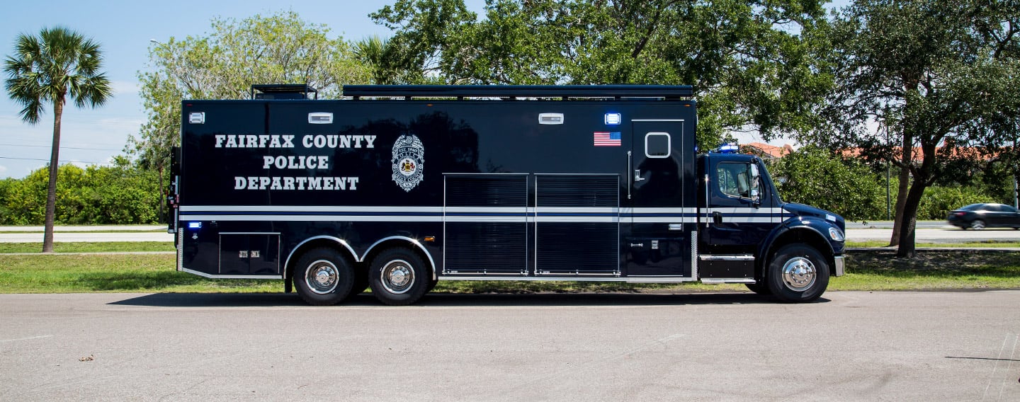 Frontline Communications vehicle parked outside near trees on a sunny day.