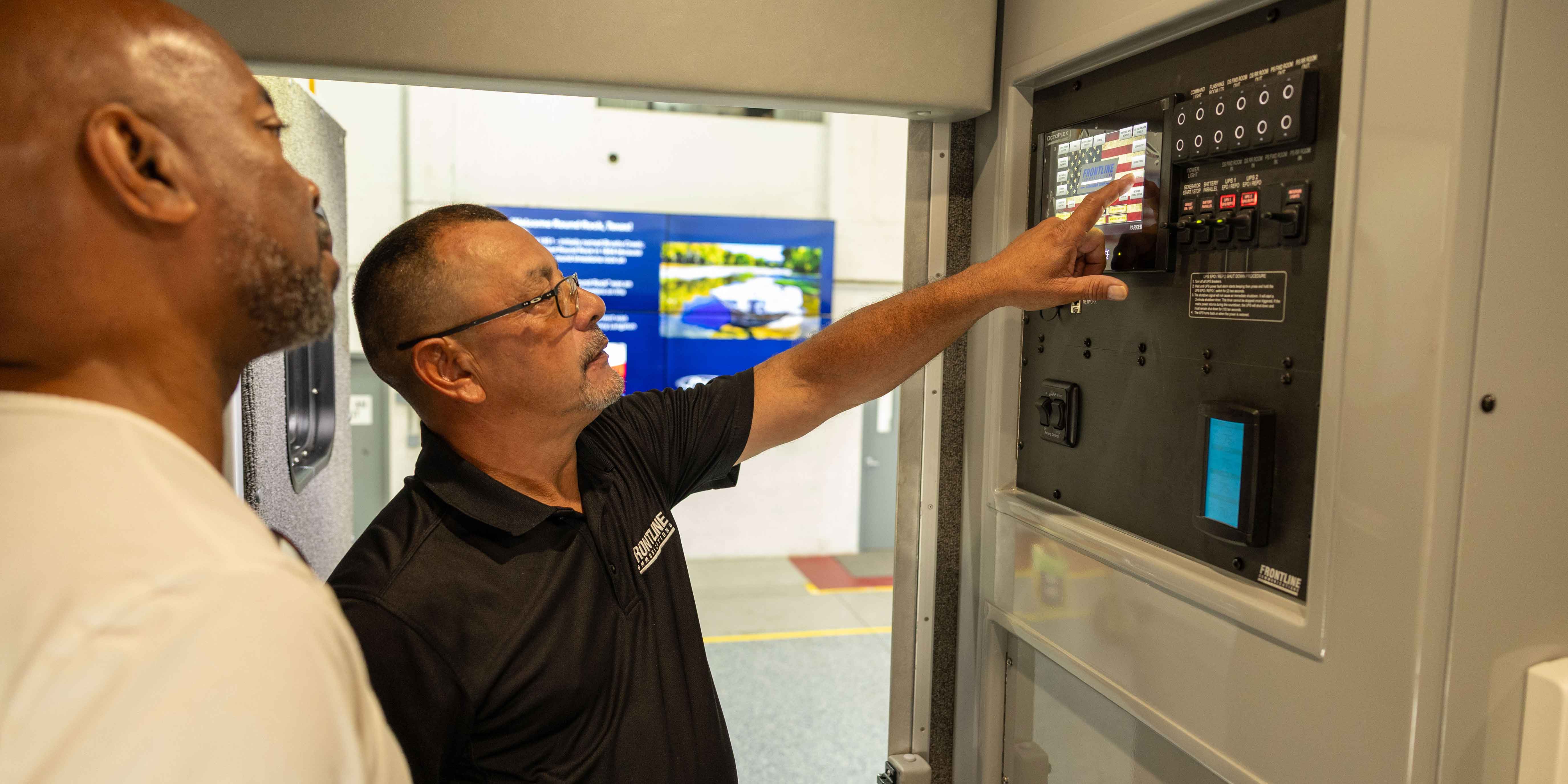 Two Frontline Communications team members servicing the interior of a vehicle.