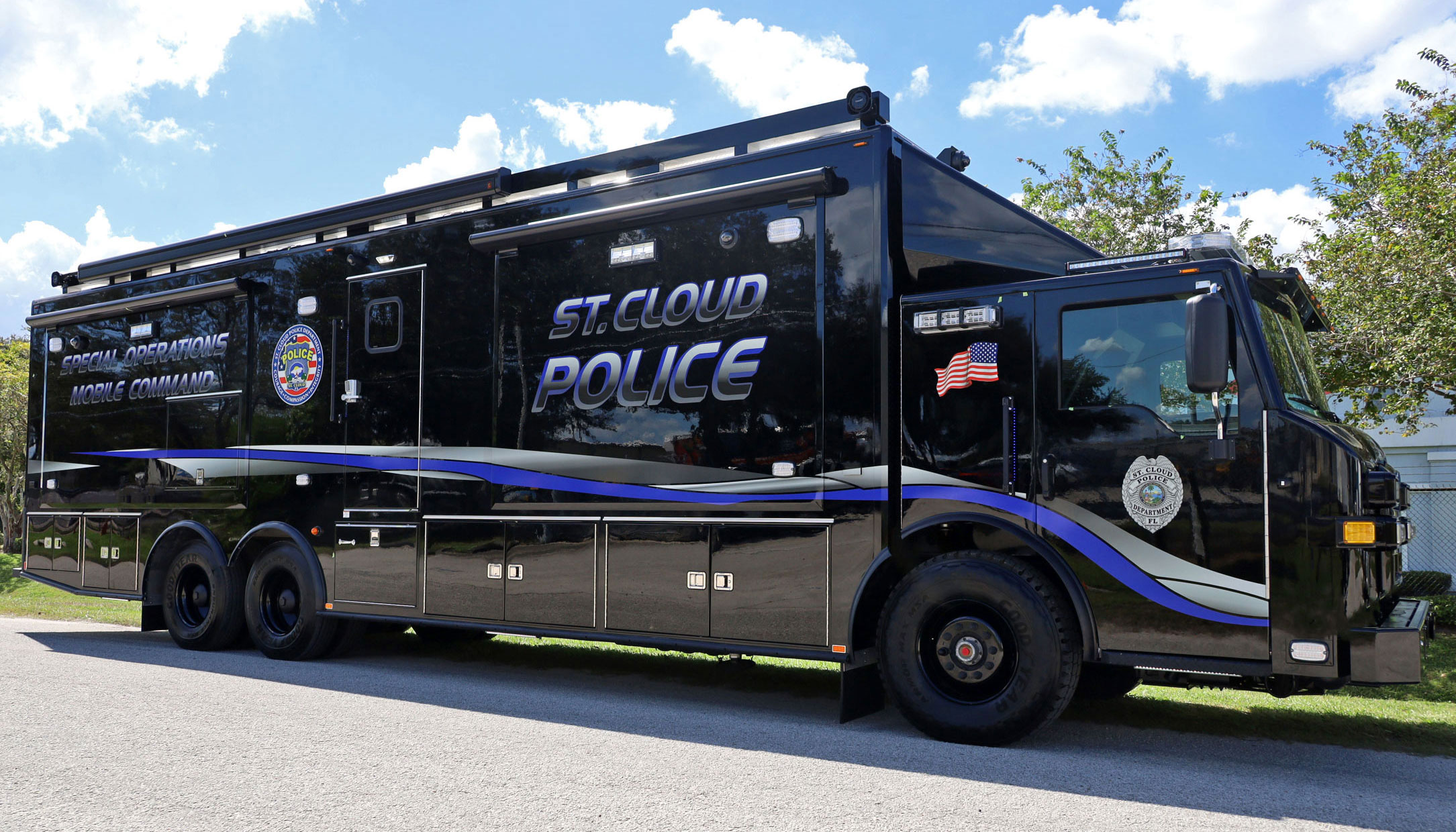 A Frontline Communications Mobile Command Vehicle for St. Cloud Police Department parked outside on a cloudy day.